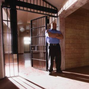 一名男性狱警站在敞开的牢房前